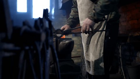 The blacksmith working in the forge, making a horseshoe. Hand made, unique vintage technology. Rare old profession