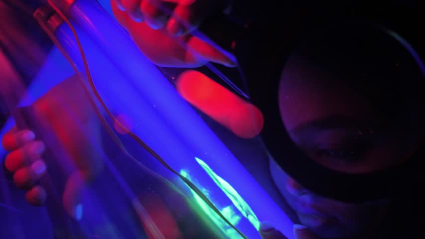 Fashion model in neon light, sight a beautiful model girl looks through a magnifying glass