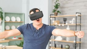 Excited young man with virtual reality headset dancing and play 360 video game at home