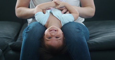 Mother tickling baby daughter. 4K cinematic real life footage.