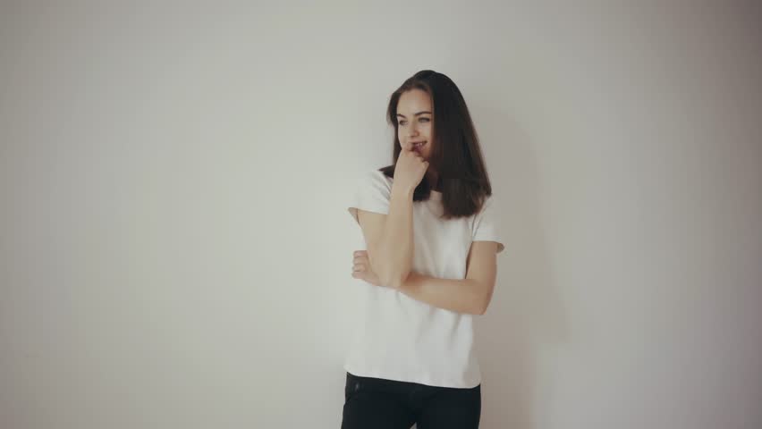 Slow motion video of a pretty hipster girl wearing white blank t-shirt and black jeans with white isolated background, touching her hair and smiling and showing the clothes for the mock-up