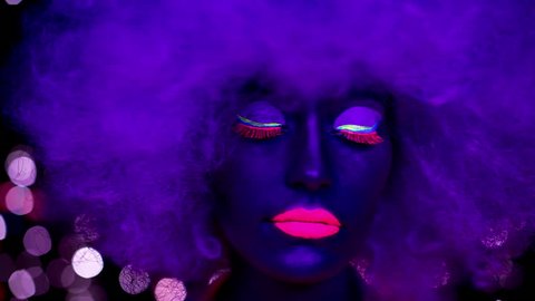 sexy cyber raver woman with large afro wig filmed in fluorescent clothing under UV black light