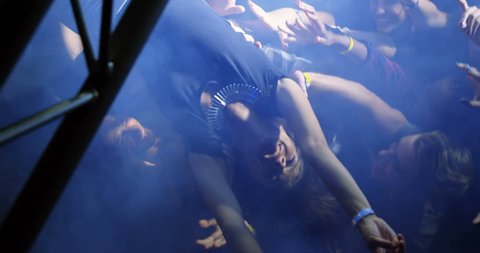 Overhead view of Caucasian woman crowd surfing at a concert in nightclub.