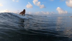 Caucasian surfer with long hair rides the ocean wave at sunrise at the Jailbreaks surf spot in Maldives. Clip contains underwater view of the spot