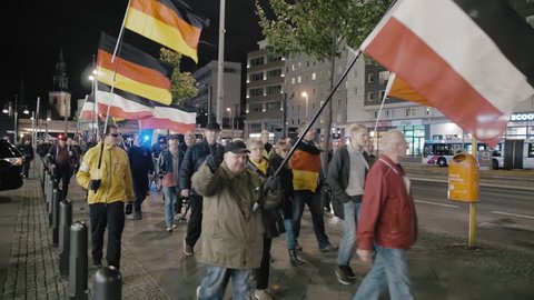 BERLIN, GERMANY - October 2018: The demonstration with the flags of the German Republic and the Third Reich neo-Nazis in the center of Berlin. The demonstrator shows a victorious sign with his hand