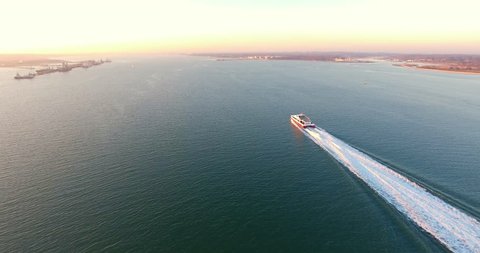 4K Aerial over the Solent Following a Isle of Wight ferry going up Southampton water during early evening sunset with small boats passing by.