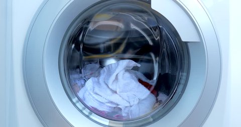 Close Up Industrial Washing Machine Washes Colored Clothing and White Linen, White Striped Clothing. Cylinder Spinning Machine. Concept Laundry Washing Machine, Industry Laundry Service.