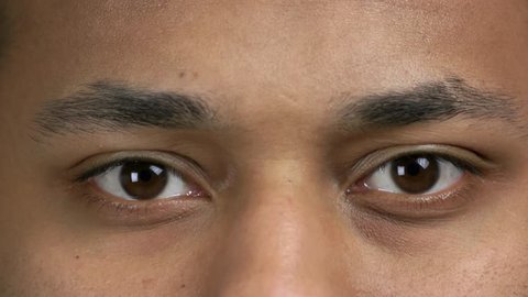 Close up brown eyes of dark-skinned man. Close up smiling face of young Indian man. Facial expressions and emotions concept.