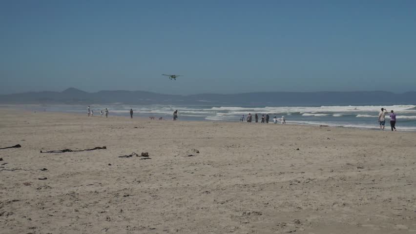 Airplane flying low over popular blue flag beach in Hermanus, South Africa.