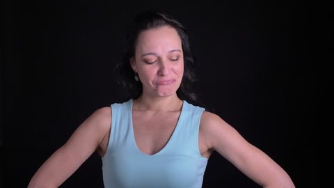Portrait of middle-aged female bodybuilder demonstrating her biceps into camera on black background.