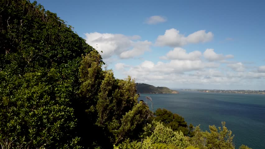 New Zealand Auckland Manukau Harbour Panoramic view of beautiful gulf pan shot left to right blue sky with some clouds trees in foreground hills and mountains and opening out to sea
