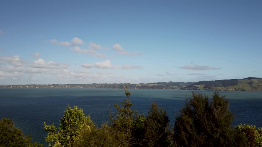New Zealand Auckland Manukau Harbour Panoramic view of beautiful gulf pan shot left to right blue sky trees in foreground hills and mountains and opening out to sea