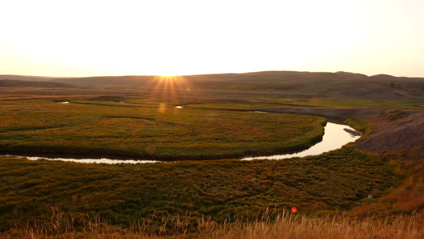 The sun sets in a clear sky over a tributary of the Lamar River in Yellowstone National Park, Wyoming.
