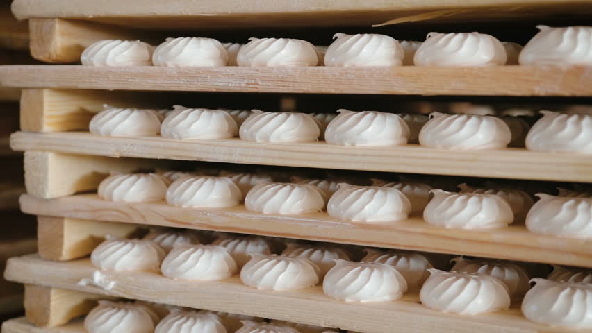 Panorama of many sweets white marshmallows stored in wooden racks in the warehouse of the confectionery factory. The concept of ready-made sweet products