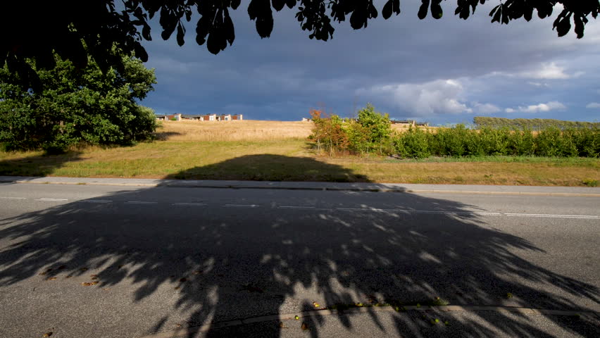 Static shot, of stormy, dark clouds above the countryside, filming from under a tree, in Aalborg, Denmark