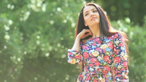 Young girl model brunette walking in the park. The beautiful long dress. Close median overall plans. The beautiful nature and the beauty of the girl.