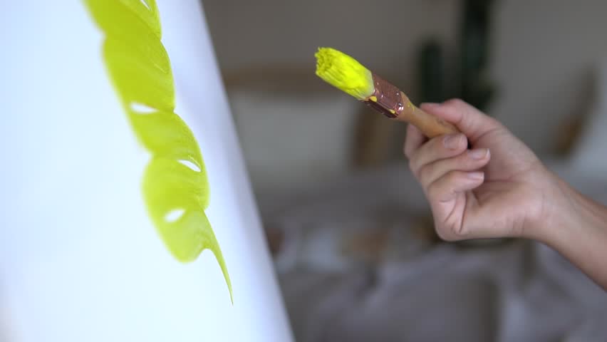Woman paints with yellow color on canvas with a brush | Shutterstock HD Video #1027688612