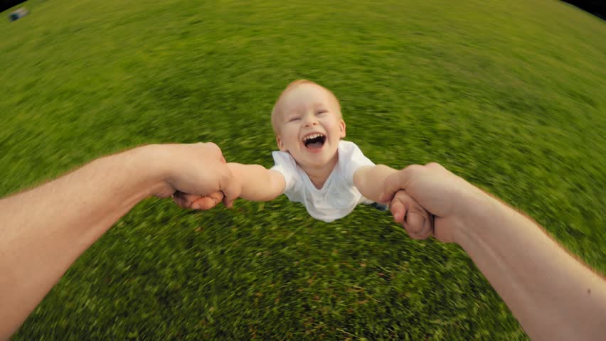 Dad hands holding spinning little happy smiling cute son playing together at nature countryside POV shot carefree family enjoying weekend relaxing having good time outdoor high angle