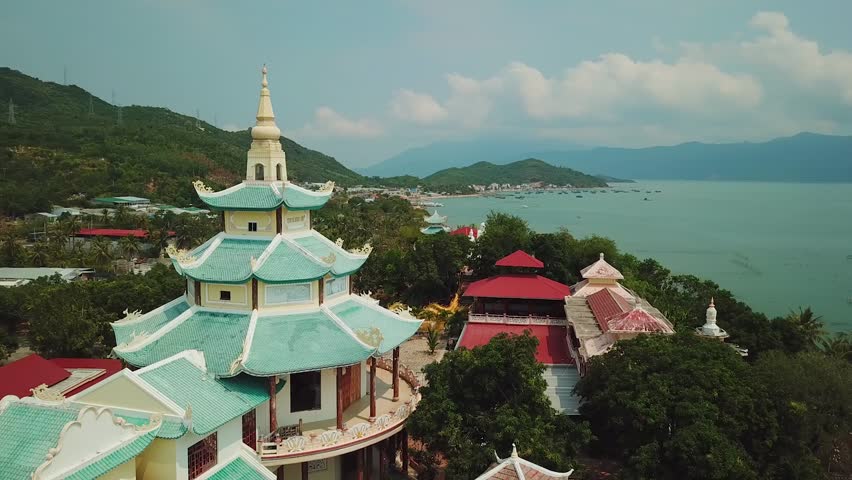 Drone around beautiful decorated dome tower buddhist asian temple palace. Nature landscape mountains sea ocean clouds sunny. Unique authentic historical reconstruction faith religion. Vietnam sight