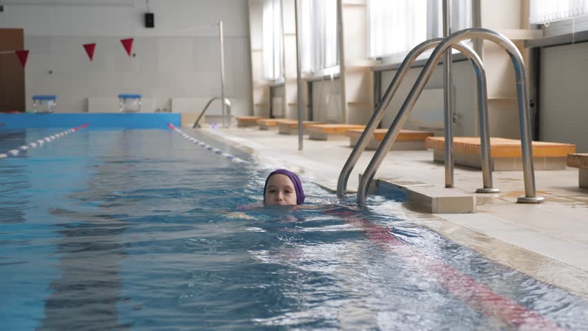 Girl child in swimming pool. Smiling child leads a healthy lifestyle and keen on sports.