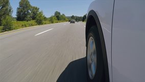 POV of car wheel on white car driving down highway