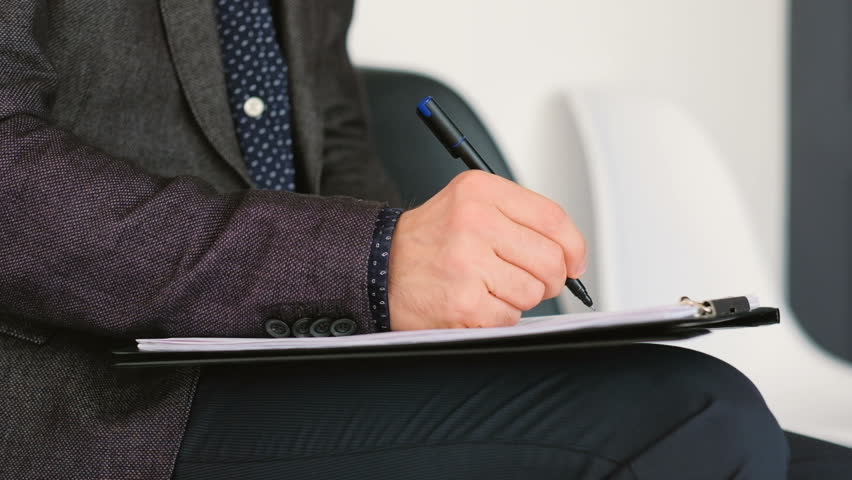 Man in black suit. Writing hand closeup. Job applicant filling in form putting ticks signing. Employment. Business meeting.