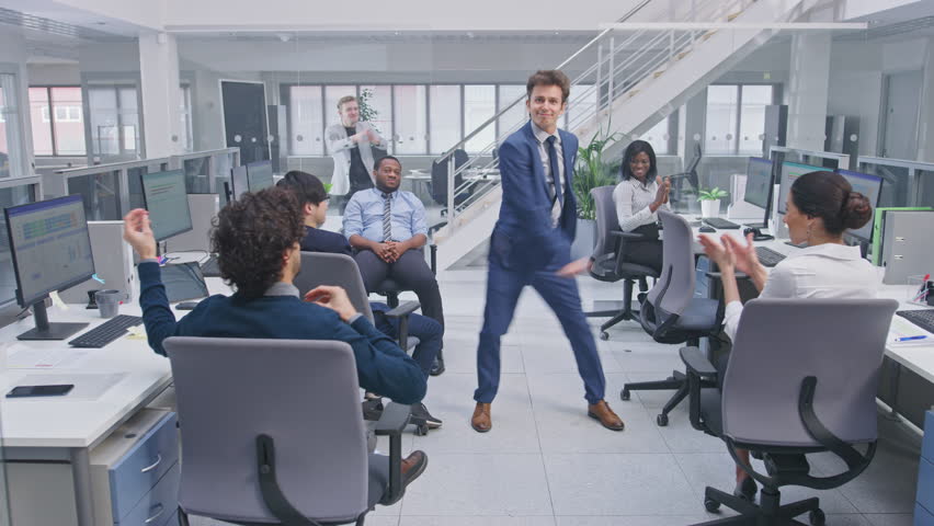 Young Happy Business Manager Wearing a Suit and Tie Dancing in the Office. Colleagues are Cheering. Diverse and Motivated Business People Work on Computers in Modern Open Office. Royalty-Free Stock Footage #1027712576