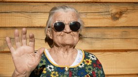 Brutal granny in sunglasses waves by hand at the camera.
Wrinkled face of aged woman. Grandmother on wooden rustic background. Old granny looks into the camera and waves by hand. 91 year old granny. - Powered by Shutterstock - Get 15% off with code: PIKWIZARD15