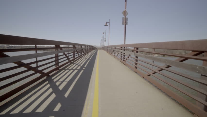 This is a POV shot of walking across a Pedestrian Bridge on a Sunny Day.
