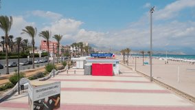 Ascending Aerial footage of San Juan beach in Alicante Spain, with mountains in the background, flying over tourism info point