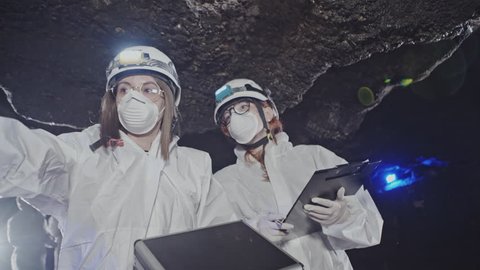 Scientists in white protective costumes investigate mysterious caves
