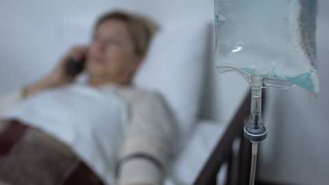 Weak lady patient talking phone and falling asleep in sickbed near drop counter