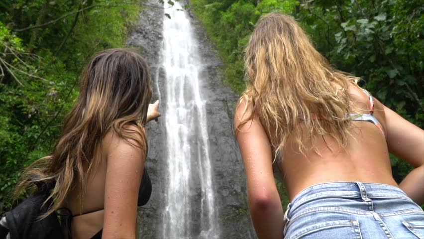 Two Females admire big waterfall and point to it in slow motion