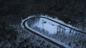 drone video at dusk in the mountains with cars driving around a hairpin