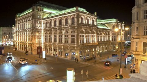 Rising crane shot of world famous Vienna State Opera with facade illuminated beautifully at night, central Vienna, Austria