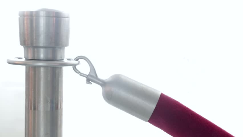 Brightly washed out view of hand opening velvet rope gate to allow access