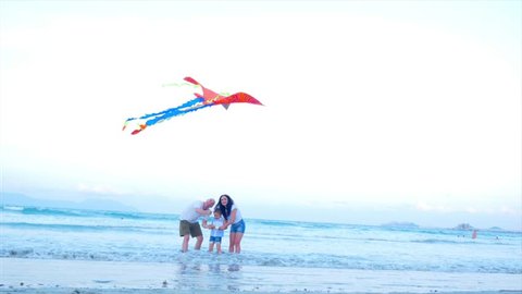 Happy Family With Child Launch a Kite, Mother Father and Daughter Playing with the Older Kite in the Ocean Background in Sunset. Concept of a Happy and Carefree Childhood. Adlı Stok Video