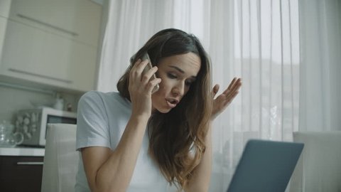 Angry woman call phone at home. Annoyed person talking mobile phone at kitchen. Upset woman using cellphone at home kitchen. Businesswoman arguing in phone conversation