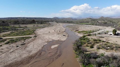 Aerial view of river crossing in desert wash seasonally flowing with water. Car drives through water
