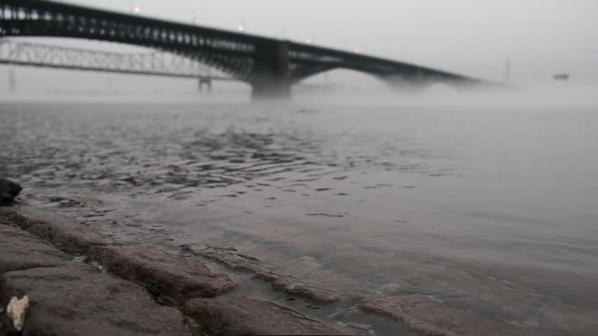 Low angle view of Eads Bridge in St. Louis, extending over the Mississippi River into thick fog.