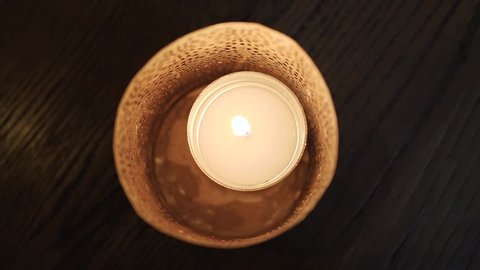 A candle from above burns inside a holder, an old bar with candles burning set the atmosphere