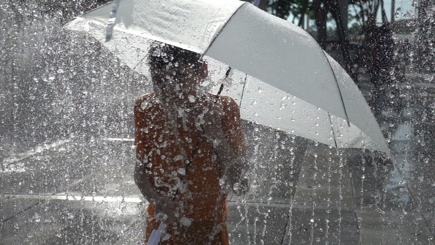 Little boy playing water drops fountain under the cloth and umbrella