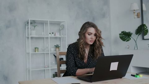 20s lady working at a desk in a trendy hipster start up office using shared data. Close up with emotion of joy and happy success. Student writing a report on successful marketing.