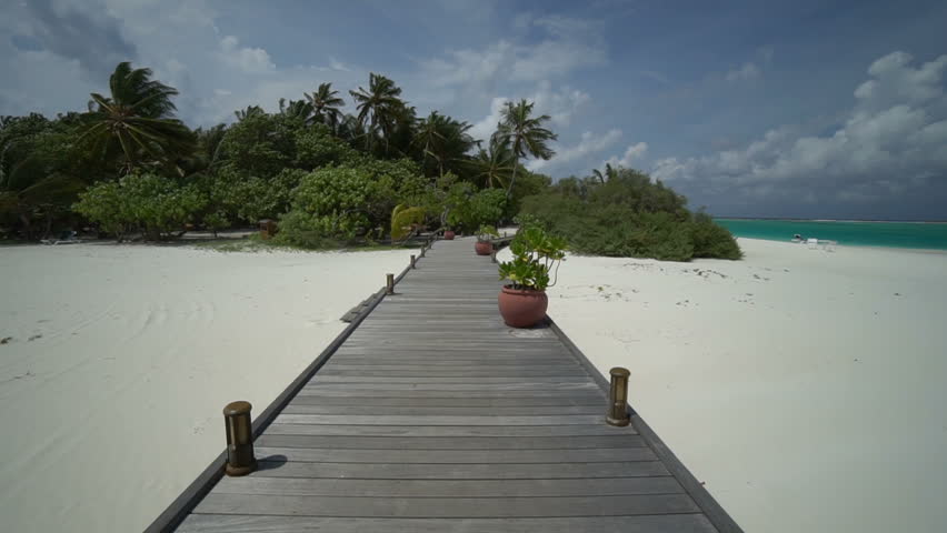 A wooden walkway path on a tropical white sandy beach, paradise island and blue sea.