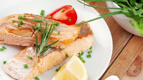 healthy fish cuisine : grilled pink salmon steaks with red caviar in white bowl lemon and vegetable salad dish with cutlery and pepper grinder over wooden table 1920x1080 intro motion slow hidef hd