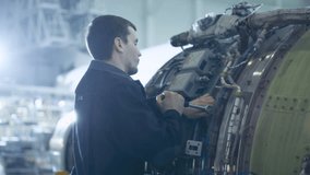 Aircraft Maintenance Mechanic Inspecting and Working on Airplane Jet Engine in Hangar, Doing Checkup, Using Wrench to Fixate all the Components Properly - Powered by Shutterstock - Get 15% off with code: PIKWIZARD15