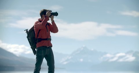 Young adventure photographer taking photographs in New Zealand. Lake with Mt Cook in background. Video clip recorded on professional camera, 10bit Pro Res.