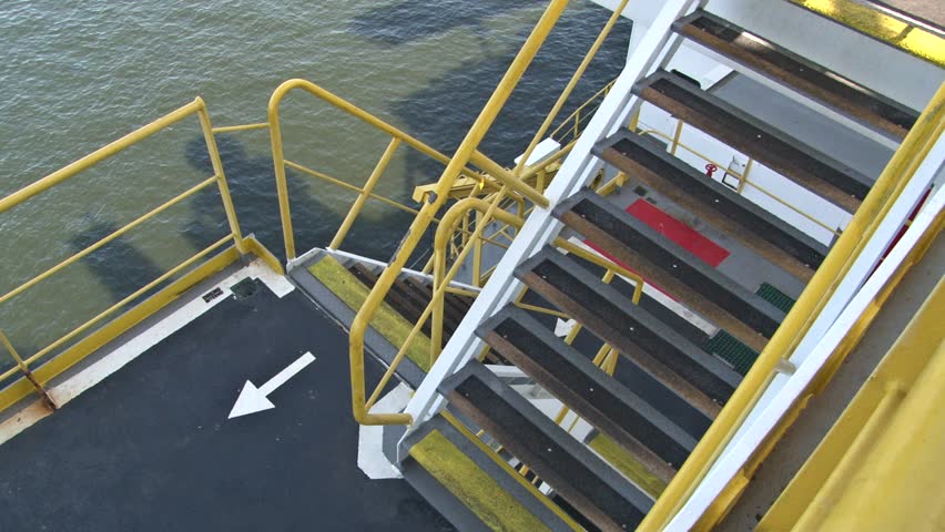 Access staircase inside an oil and gas offshore platform with a sign direction to exit on the safety range way, the sea in on the background.