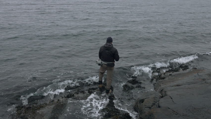 Slow motion waves and fisherman. Waves washing over his feet.