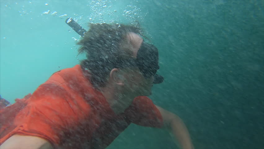 Young man dives and swims under the breaking wave and moving against the powerfull stream